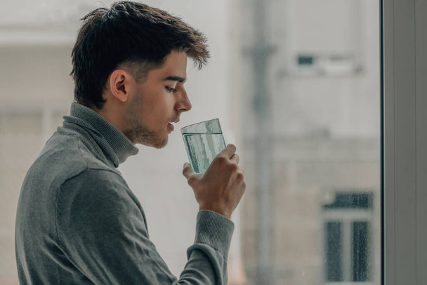 mladý muž doma pije sklenici vody - Fotografie, Obrázek
