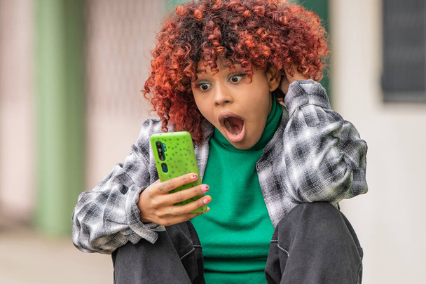 afro americano negro chica mirando móvil en la calle sorprendido - Foto, imagen