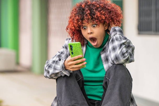 afro americano nero ragazza guardando cellulare in il strada sorpreso - Foto, immagini