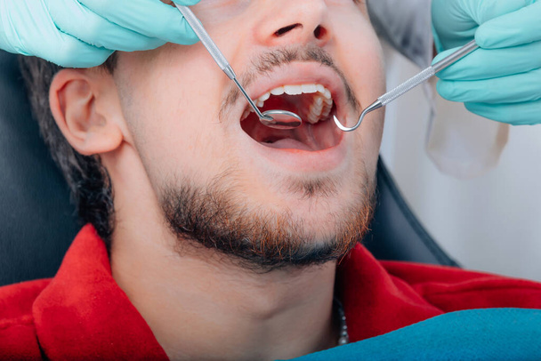 пациент в стоматологическом кабинете, руки с инструментами стоматолога - Фото, изображение