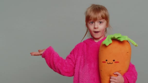 Щаслива дівчинка, яка показує великі пальці вгору вказуючи порожнє місце, рекламну площу для комерційного тексту, копіює простір для просування товарів. Маленька маленька дитина. Студійний знімок у приміщенні на сірому фоні стіни
 - Кадри, відео