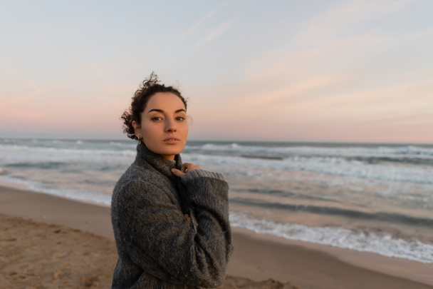 Молода жінка дивиться на камеру, стоячи на розмитому пляжі в Барселоні.  - Фото, зображення