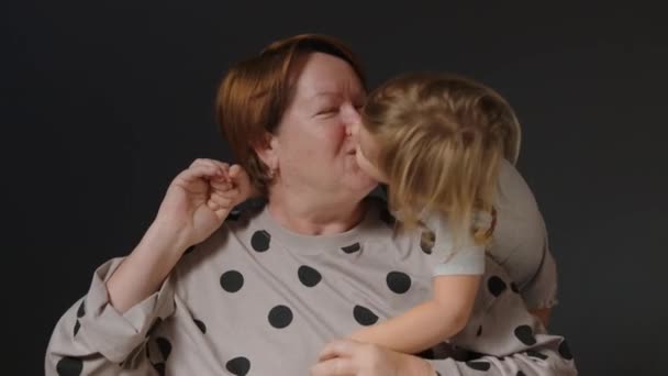 Het concept van familie liefde en liefde tussen generaties. Mooie kleindochter kust en knuffelt haar oudere grootmoeder. Hoge kwaliteit 4k beeldmateriaal - Video