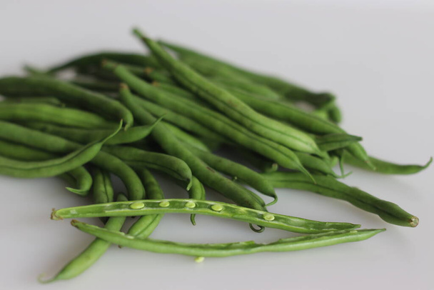 Bunch of French Beans shot on white back ground with few sliced half. It is also called green beans, bush beans, string beans, snap beans, haricot vert. Scientific name is Phaseolus vulgaris. - Foto, Imagem