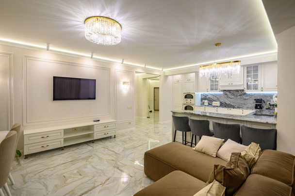 Apartamento estudio con cocina clásica con isla que sirve como comedor y televisor en la pared - Foto, Imagen