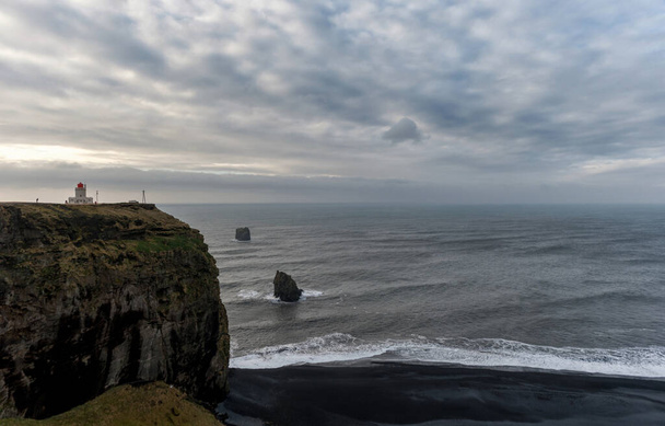 アイスランドの灯台と黒砂のビーチレイニスフィヤラ。背景にある朝の空と岩。広角. - 写真・画像