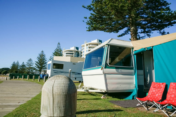 Summer holiday caravans parked under Norfolk Pine tree with outdoors seats. - Fotoğraf, Görsel