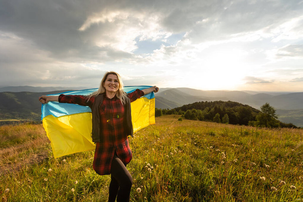 Vrouw met een gele en blauwe vlag van Oekraïne in de buitenlucht. Onafhankelijkheidsdag. Vlaggendag. Grondwettelijk dag. Vrouw in traditioneel borduurwerk met vlag van Oekraïne - Foto, afbeelding
