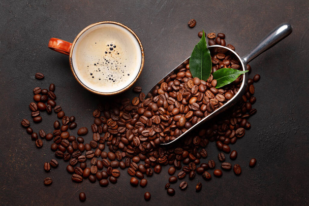 Roasted coffee beans in scoop and cup of espresso. Flat lay on stone table - Photo, Image