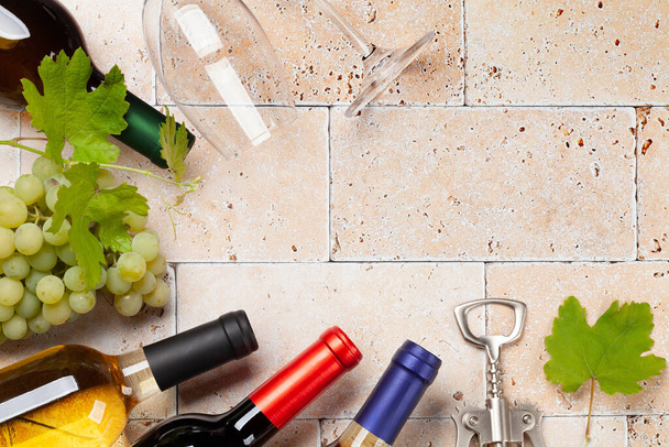 Various wine bottles, glasses and corkscrews on stone table. Flat lay with copy space - Photo, Image