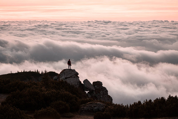 Traveler standing on cliff edge mountain top above sunset clouds travel adventure lifestyle summer journey vacations. - Foto, Imagem