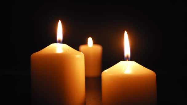 Drei Kerzen brennen mit einer weichen gelben Flamme im Dunkeln und werden vom Wind gelöscht. Zeitlupe. - Filmmaterial, Video