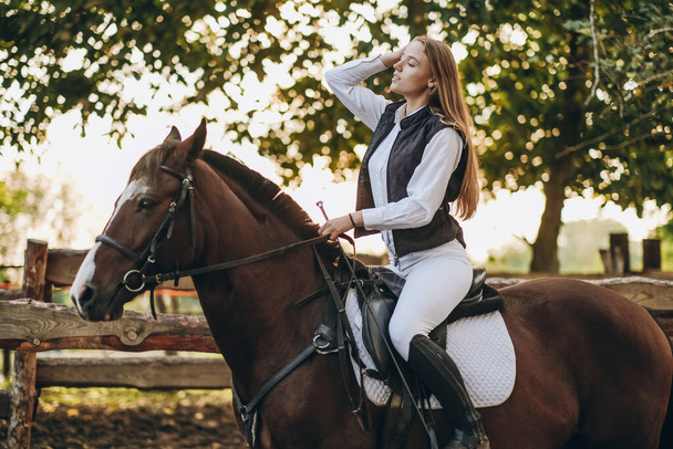 若い女性のジョッキーがジャンプ訓練で馬の上に座っている。競争の準備だ。馬への愛. - 写真・画像