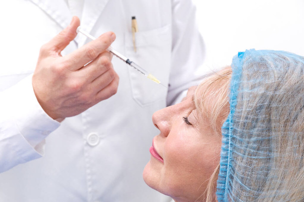 Lähikuva kuva atraktiivinen kypsä nainen ottaen hyaluronihappo injektiot ja Botox esteettinen klinikalla. Ei-kirurginen hoito vähentää ryppyjä ja välttää ikääntymistä. Konsepti: kauneudenhoito - Valokuva, kuva