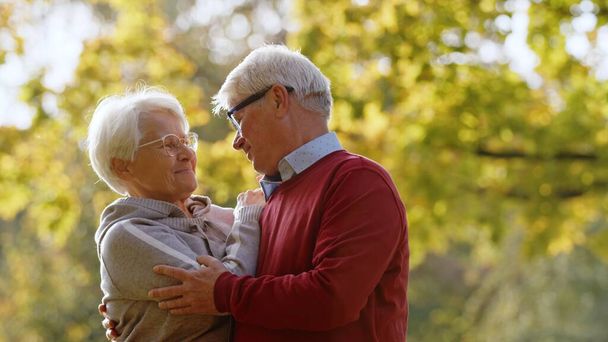 Two loving grey-haired people together outdoor in autumn nature. High quality photo - Foto, Imagem