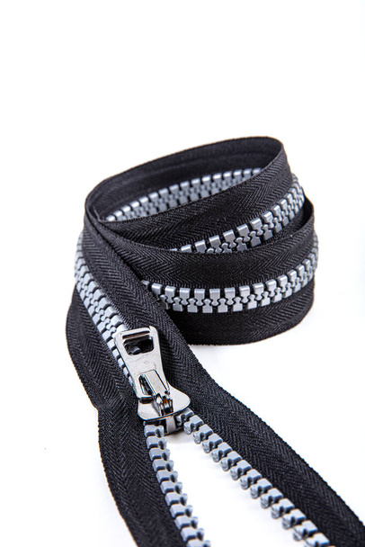 Jacket Winter Coat Black Tape Heavy Duty Zippers Large Molded Plastic Zippers. Close-up of zipper slider on a white surface. Sewing production, materials and accessories. - Foto, afbeelding