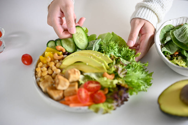Женщина делает здоровый зеленый салат или миску для салата Будды на завтрак. Веганская еда, диетическое меню, блюдо с высоким содержанием белка и питательных веществ. обрезанное изображение - Фото, изображение