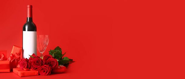 Пляшка вина, трояндові квіти, скло і подарунки на червоному фоні з простором для тексту. День святого Валентина. - Фото, зображення