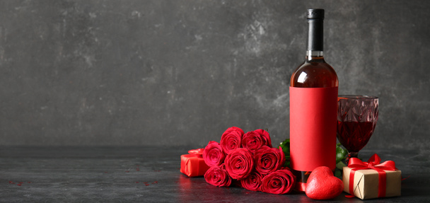 Bottle of wine, rose flowers, glass and gift on grunge background with space for text. Valentine's Day celebration - Photo, Image
