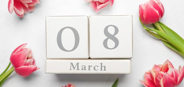 Calendar with date of International Women's Day and tulip flowers on white background - Foto, imagen