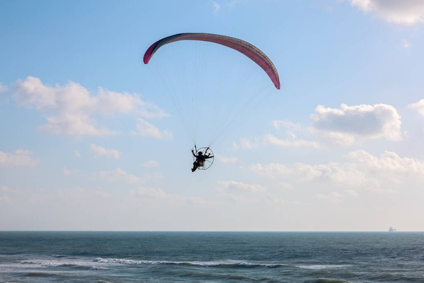 Parachutist flying over sea on summer day - Foto, afbeelding