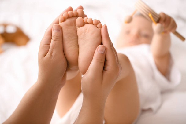 Мама массирует ноги своего ребенка в спальне, крупным планом - Фото, изображение