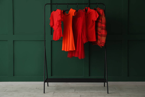 Rack with red female clothes near green wall - Fotoğraf, Görsel