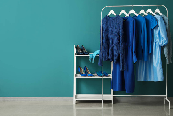 Rack with blue clothes and shoe stand near color wall - Fotografie, Obrázek