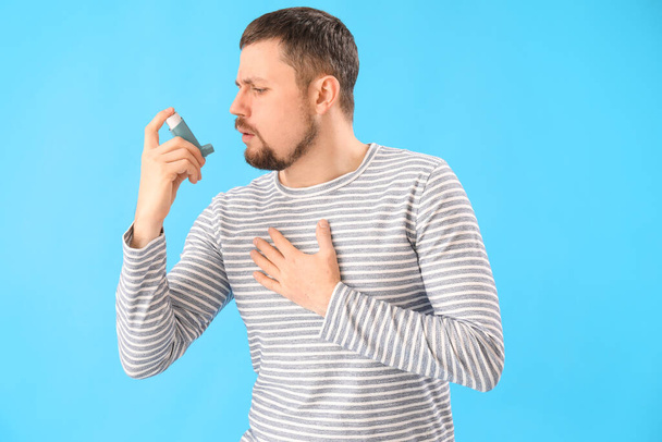 Sick man with inhaler on blue background - Photo, Image