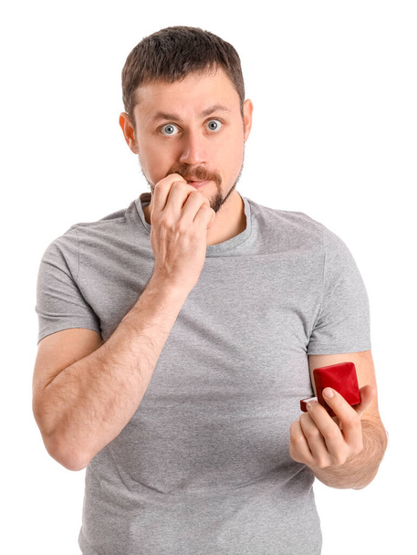 Hezký muž s zásnubní prsten kousání nehty na bílém pozadí - Fotografie, Obrázek