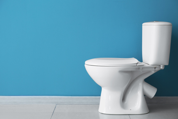 Κεραμική λεκάνη τουαλέτας κοντά σε μπλε τοίχο - Φωτογραφία, εικόνα