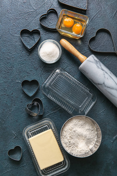 Σύνθεση με υλικά και σκεύη για την προετοιμασία γευστικών μπισκότων σε σκούρο φόντο. Γιορτή του Αγίου Βαλεντίνου - Φωτογραφία, εικόνα