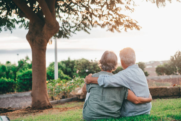 Head shot close up portrait happy grey haired middle aged woman snuggling to smiling older husband, enjoying tender moment at park. Bonding loving old family couple embracing, looking sunset. - Zdjęcie, obraz