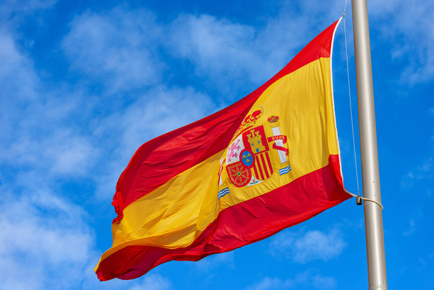 雲とコピースペースを持つ青い空に対して風に吹くスペインの旗の閉鎖。スペイン広場(Plaza de Espana) 、マドリード中心街、スペイン、南ヨーロッパ. - 写真・画像