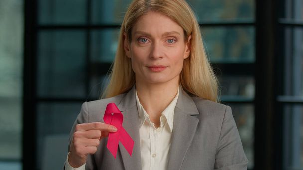 Headshot portrait Caucasian middle-aged woman hold red ribbon in office businesswoman with HIV AIDS awareness disease prevention protection sign volunteering activity charity. World breast cancer day - Foto, afbeelding