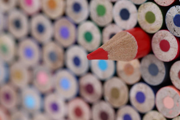 Много разноцветных карандашей и один выделяется красным. Мышление по-другому и концепция успеха бизнеса - Фото, изображение