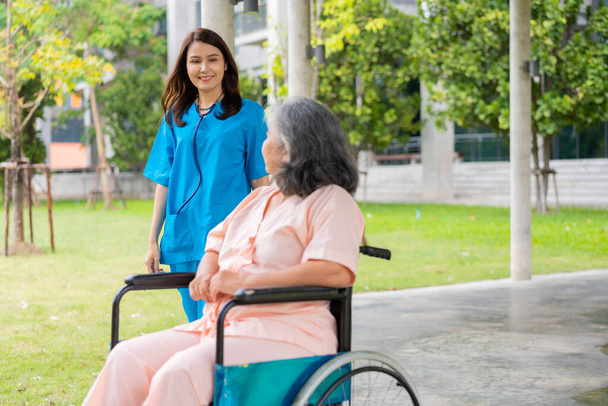 Asiatique soignant soignant ou infirmière tenir la main du patient et encourager le patient dans un fauteuil roulant. Concept de retraite heureuse avec les soins d'un soignant et de l'épargne et de l'assurance-maladie des aînés. - Photo, image