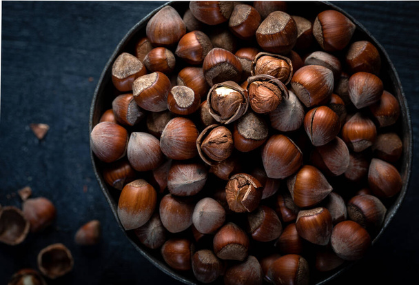 Above view of a wooden bowl with hazelnuts. Hazelnuts in a bowl on a dark background. Close-up. Top view. - Foto, Imagen
