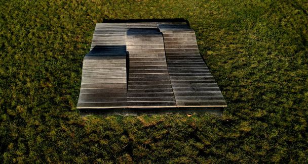 deck chair composed of three waves which are made of wood and board. large seating elements in a landscape park. furniture for tenagers, aerial view, green, three parts, drone point of view, beach - Zdjęcie, obraz