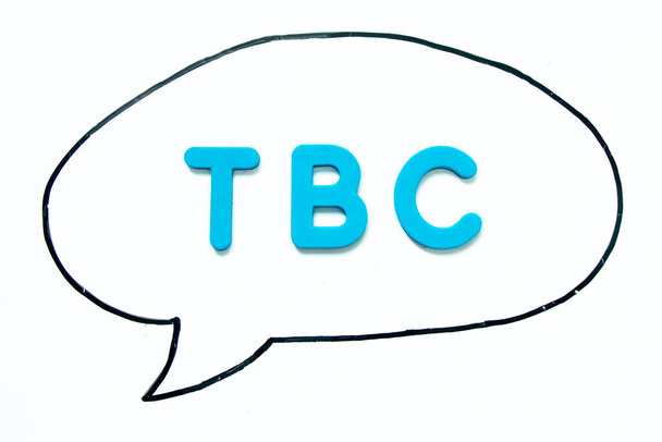 ホワイトボードの背景にバブルスピーチとして黒の線画で単語TBC(確認または継続する省略)とアルファベット文字 - 写真・画像