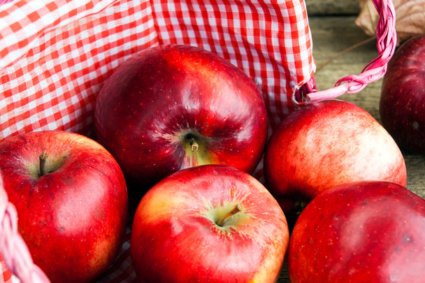 Manzanas rojas en una canasta sobre fondo de madera
 - Foto, Imagen