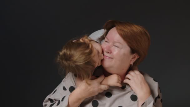 Het concept van familie liefde en liefde tussen generaties. Mooie kleindochter kust en knuffelt haar oudere grootmoeder. Hoge kwaliteit 4k beeldmateriaal - Video