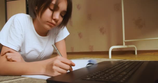 Close-up video of a schoolgirl doing homework online in front of a laptop monitor. Online education concept. Slow motion 4k footage. - Materiaali, video