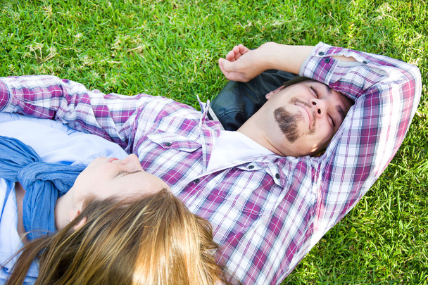 Pariskunta makaa nurmikolla puistossa
 - Valokuva, kuva