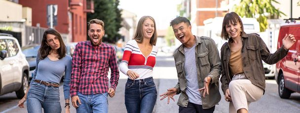 Horizontal banner or header with multicultural friends walking at city center acting funny crazy moves - Happy guys and girls having fun by urban streets on party mood - Students in travel vacations - Foto, Bild