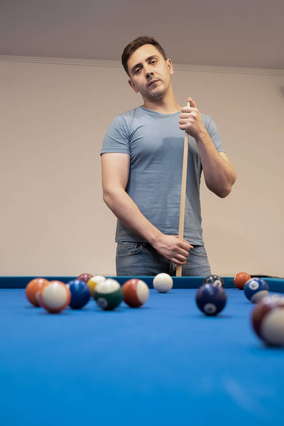 a man holds his hand on a pool table, plays snooker or prepares to shoot billiard balls, port game snooker billiards, billiard balls, play billiards - Foto, Imagen