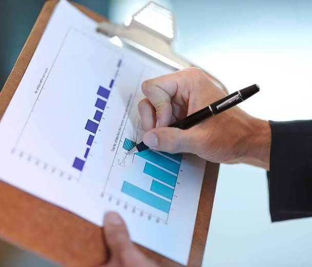 Forecasting future growth. Cropped image of a businessman making notes on a bar graph - Foto, afbeelding