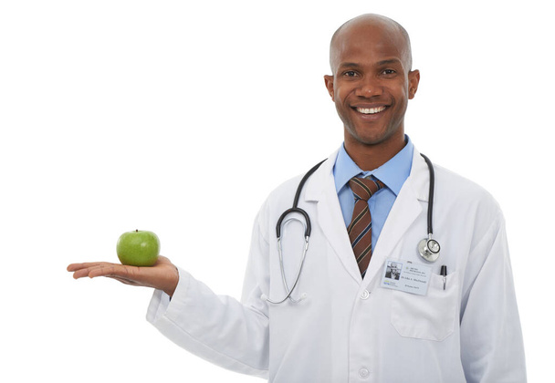 Не забывайте соблюдать здоровую диету. Обрезанный студийный образ молодого врача, держащего яблоко - Фото, изображение