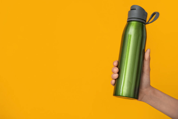 Woman holding sports water bottle on color background - Foto, immagini