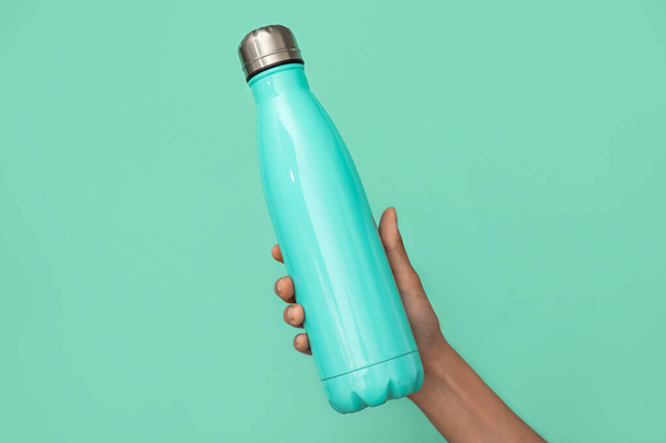 Female hand with sports water bottle of water on color background - Foto, imagen